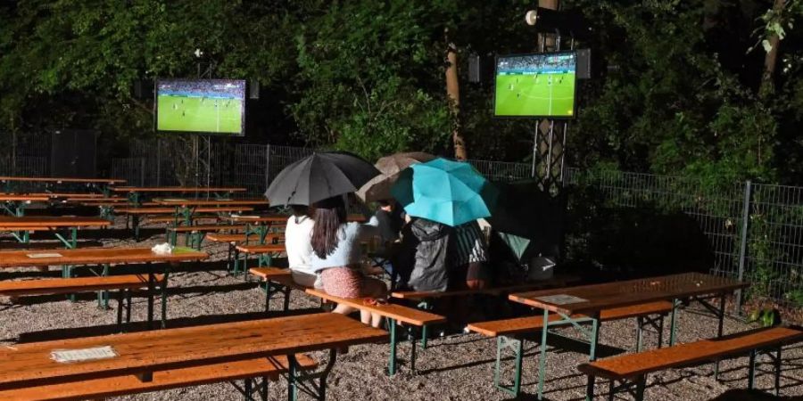 Fans verfolgen das deutsche Spiel in einem Münchner Biergarten. Foto: Tobias Hase/dpa