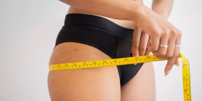 Kann man auch ohne Sport abnehmen? Frau misst Gesäss