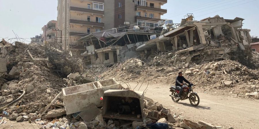 Ein Mann fährt auf einem Motorrad zwischen zerstörten Häusern im türkischen Ort Kirikhan nahe der syrischen Grenze hindurch.