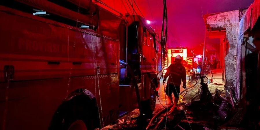 Feuerwehrleute kämpfen gegen die Flammen in umliegenden Häusern