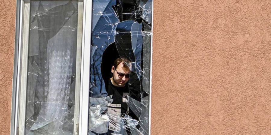 HANDOUT - Ein Mann betrachtet das zerbrochene Fenster seines Hauses nach Beschuss durch die Ukraine. Foto: Uncredited/AP/dpa - ACHTUNG: Nur zur redaktionellen Verwendung und nur mit vol...