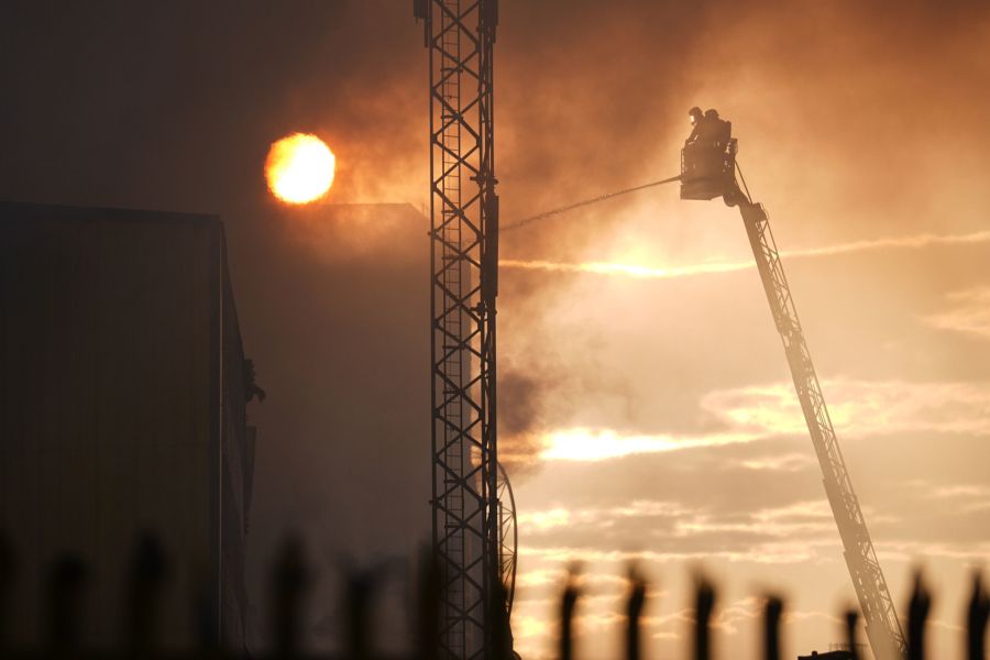 Spektakuläre Kulisse: Ein Feuerwehrmann bekämpft die Flammen von einer Drehleiter aus – vor einem glutrot gefärbten Londoner Abendhimmel.