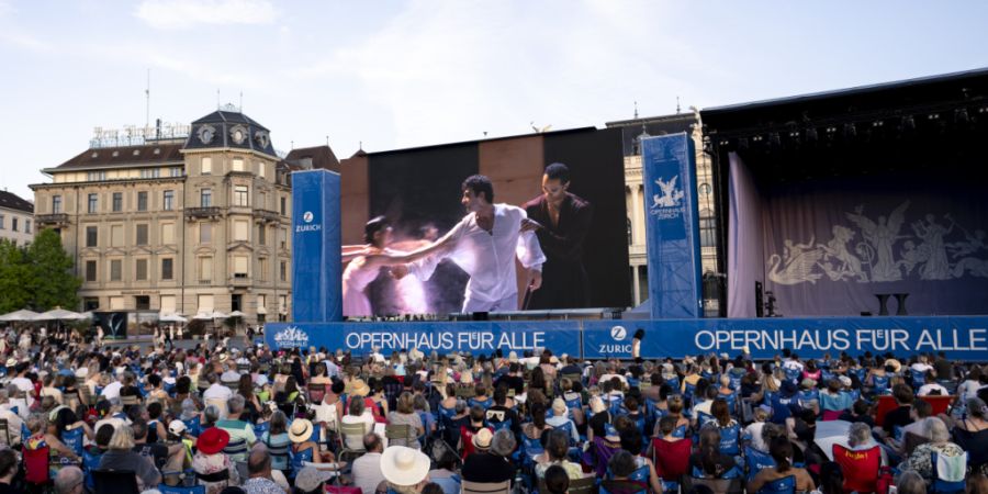 Zuschauerinnen und Zuschauer schauen auf dem Sechseläutenplatz auf einem Bildschirm das Ballettstück «Romeo und Julia» an.