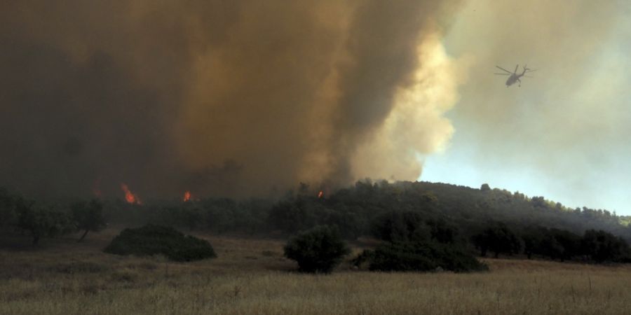 ARCHIV - Ein Hubschrauber fliegt über einem Waldbrand in der Nähe des Dorfes Vatontas. Foto: Thodoris Nikolaou/AP/dpa
