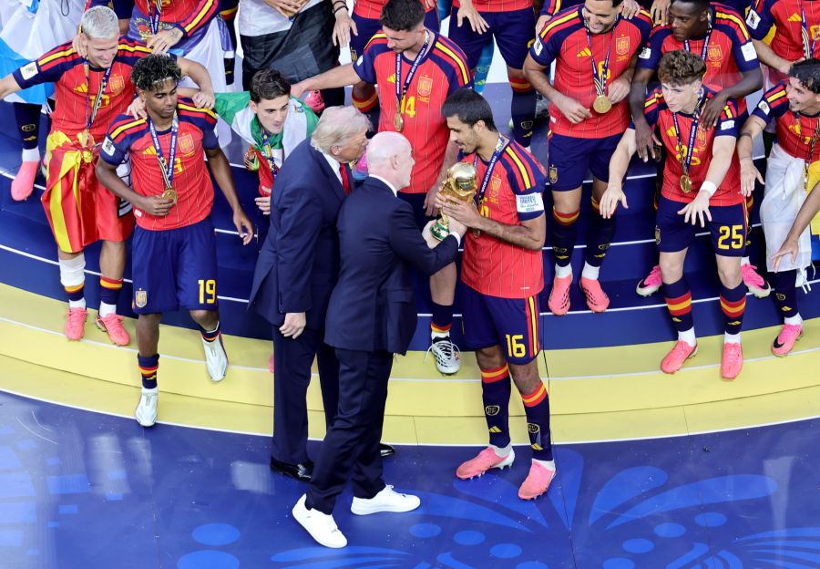 Trump und Infantino übergeben Spaniens Kapitän Rodri den WM-Pokal, umringt von den spanischen Spielern.