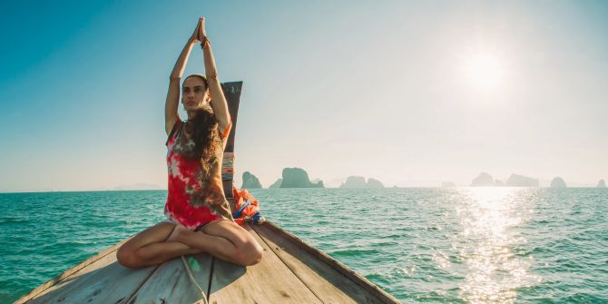 Frau macht Yoga auf einem Holzboot.