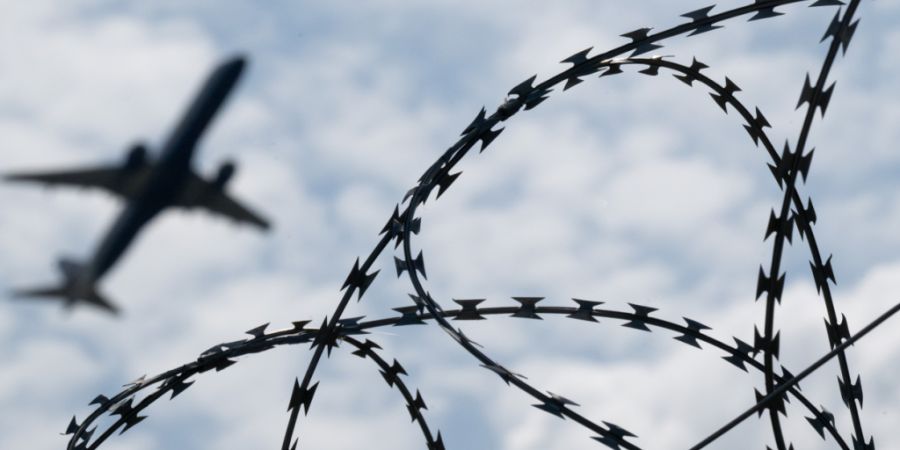 ARCHIV - Ein Flugzeug hebt am Flughafen BER hinter einem Zaun mit Natodraht ab. Foto: Sebastian Gollnow/dpa