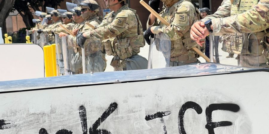 ARCHIV - Soldaten der kalifornischen Nationalgarde stehen hinter einer Absperrung, auf die «Fuck ICE» aufgesprüht wurde. Foto: Benno Schwinghammer/dpa/Archivbild