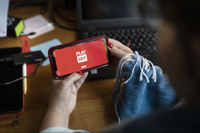 Eine Frau schaut sich das Programm des Play SRF Streamingdienstes auf einem Smartphone an. Play SRF SRG-Initiative