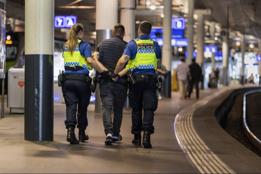 Mehrere Polizisten führen drei junge Männer in Handschellen ab. (Archivbild)