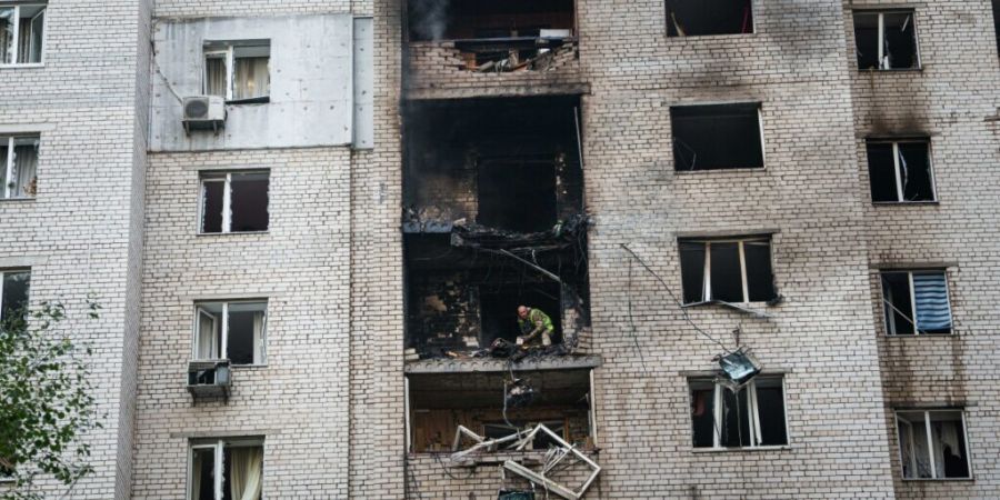 Ein Polizeibeamter wirft vom Balkon eines Hauses, das bei einem russischen Angriff auf ein Wohnviertel in Kiew beschädigt wurde, Trümmerteile einer «Shahed»-Drohne hinunter. Foto: E...