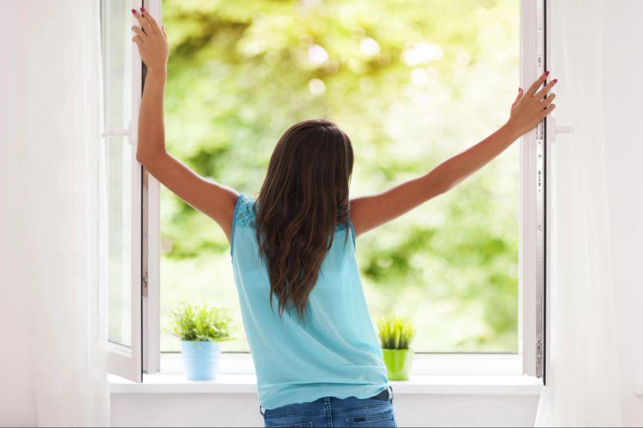 Frau öffnet Fenster.