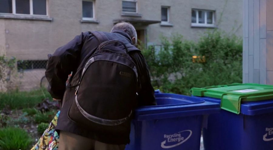 Ein Mann sucht in Containern von Denner nach Lebensmitteln.