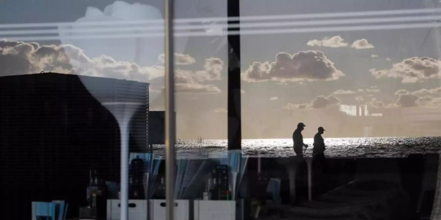 Menschen spiegeln sich im Fenster einer geschlossenen Bar in der Schinkenstrasse. Foto: Clara Margais/dpa
