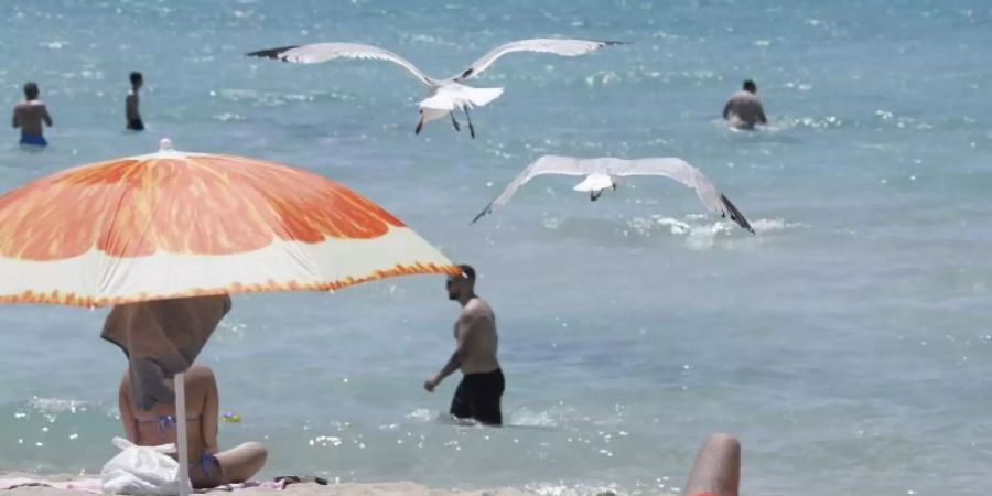 Touristen geniessen die Sonne am Strand von Arenal. Foto: Clara Margais/dpa