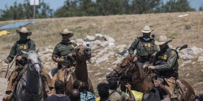 Beamte der US-Zoll- und Grenzschutzbehörde auf Pferden versuchen, Migranten bei der Überquerung aufzuhalten. Grenzstadt Del Rio