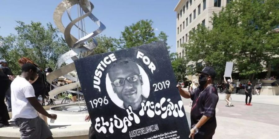 Demonstranten tragen während einer Kundgebung vor dem Polizeirevier wegen des Todes von Elijah McClain ein Plakat mit dessen Bild. Foto: David Zalubowski/AP/dpa
