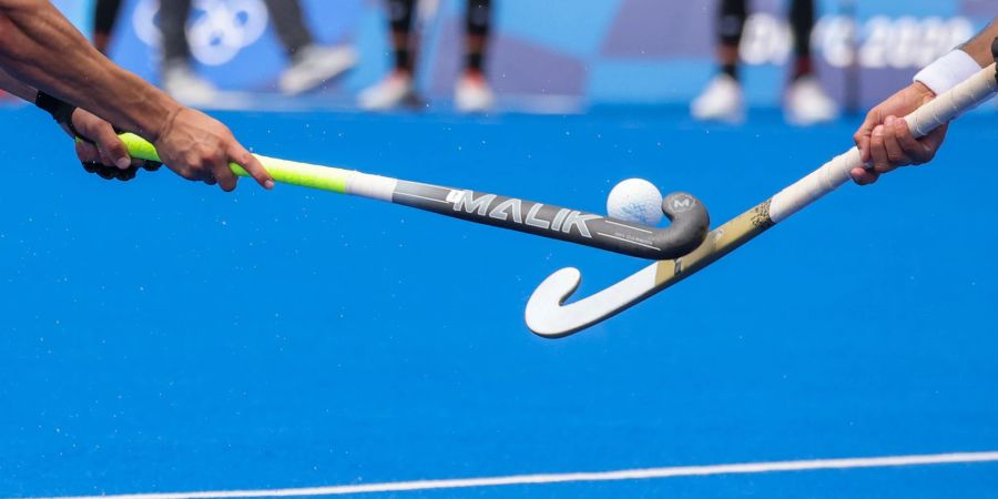 Zwei Spieler kämpfen mit den Hockeyschlägern um den Ball.