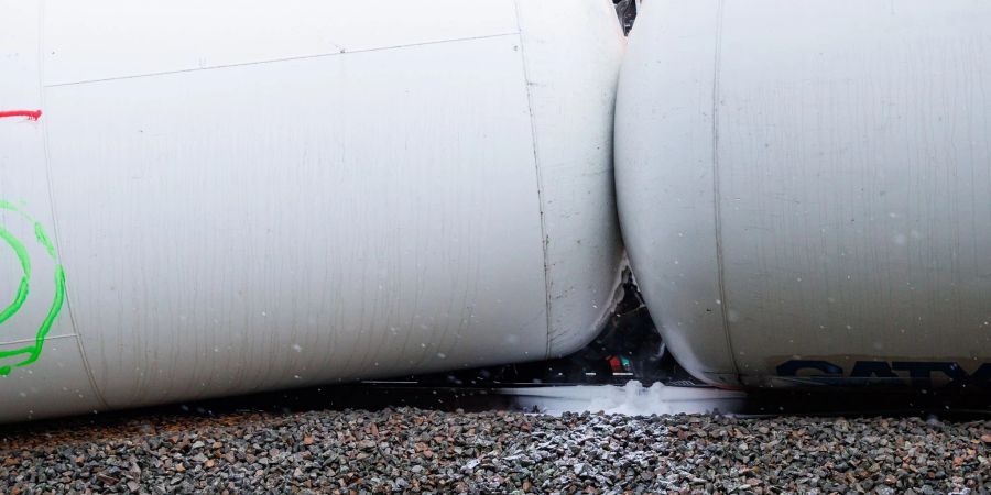 Zwei Kesselwaggons von einem der verunfallten Güterzüge liegen seitlich auf dem Bahndamm, während Propangas aus den Waggons entweicht (M).