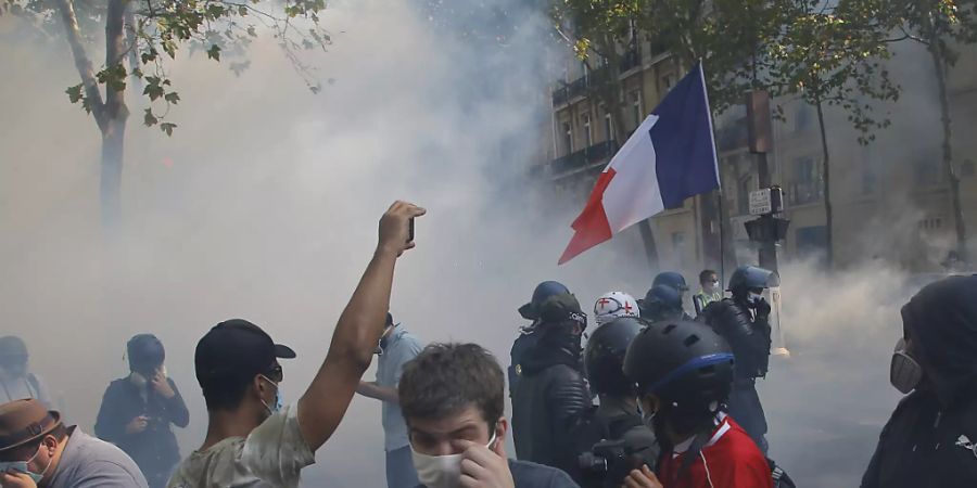 «Gelbwesten»-Demonstranten gehen in Paris vor Tränengas in Deckung. Foto: Michel Euler/AP/dpa
