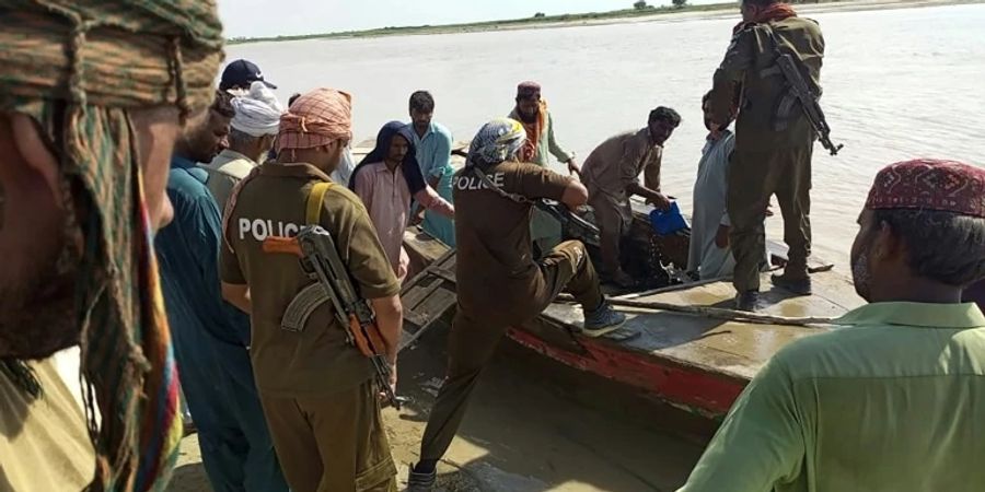 Polizisten und Anwohner besteigen ein Boot, um nach Überlebenden des Schiffsunglücks in Punjab zu suchen