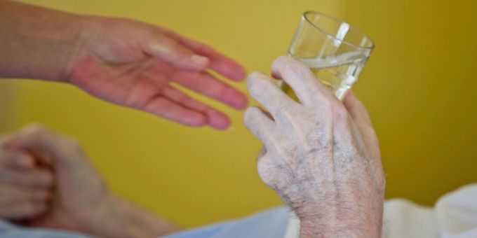 Eine Krankenpflegerin reicht einem Patienten ein Glas Wasser. Eine Krankenpflegerin reicht einem Patienten ein Glas Wasser.