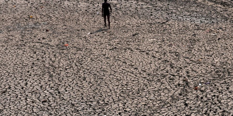 Eine Person geht durch ein ausgetrocknetes Flussbett des Flusses Yamuna, dessen Wasserstand infolge des heissen Wetters gesunken ist. Die indische Hauptstadt befindet sich, wie viele andere Teile Südasiens, inmitten einer rekordverdächtigen Hitzewelle.