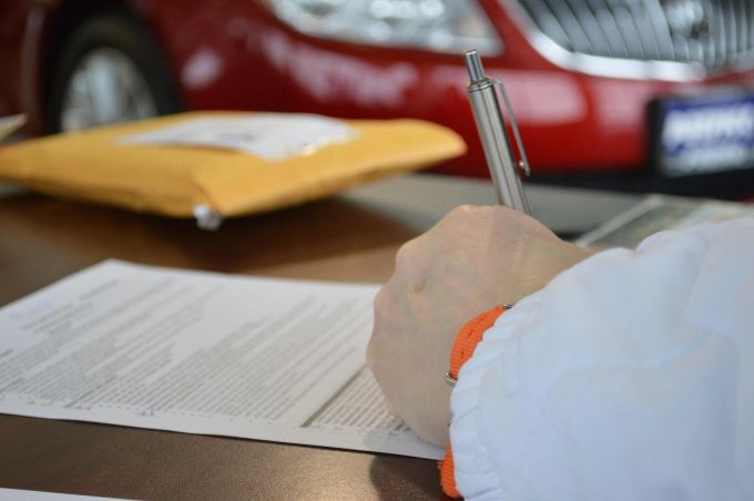 Auch wer sich einen Wagen von einem Freund ausleiht, sollte einen Vertrag aufsetzen, um für unerwartete Folgen gewappnet zu sein. Vertrag Hand Auto rot