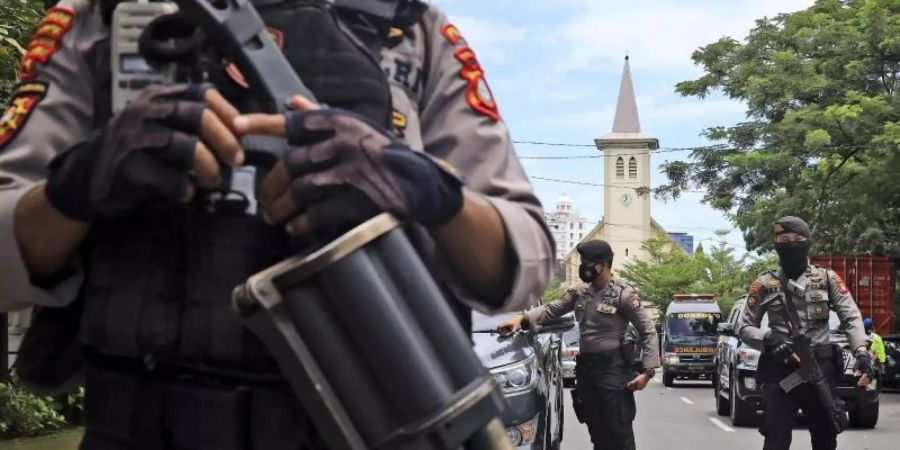 Bewaffnete Polizisten sichern die Umgebung ab. Foto: Yusuf Wahil/AP/dpa