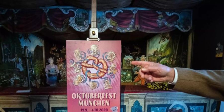 Das Siegermotiv des Wettbewerbs um das neue Oktoberfest-Werbeplakat vor einer alten mechanischen Schiessbude. Foto: Lino Mirgeler/dpa