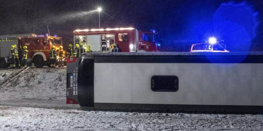 Ein Reisebus liegt umgestürzt neben der B10 bei Tomerdingen nördlich von Ulm in einem Feld. Bei schneeglatter Fahrbahn und starkem Wind kam der Bus von der Strasse ab. Foto: Stefan Puchner/dpa