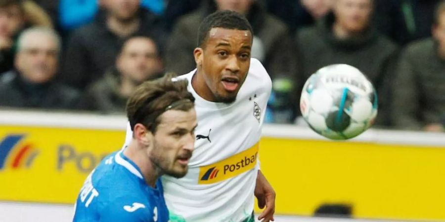 Gladbachs Alassane Plea (r) und Havard Nordtveit von der TSG 1899 Hoffenheim kämpfen um den Ball. Foto: Roland Weihrauch/dpa