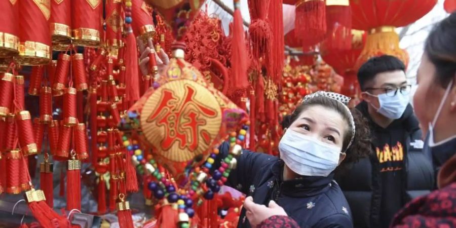 Nur mit Mundschutz: Menschen kaufen auf einem Markt in Fuyang Dekoration für das bevorstehende Neujahrsfest. Foto: CHINATOPIX/AP/dpa