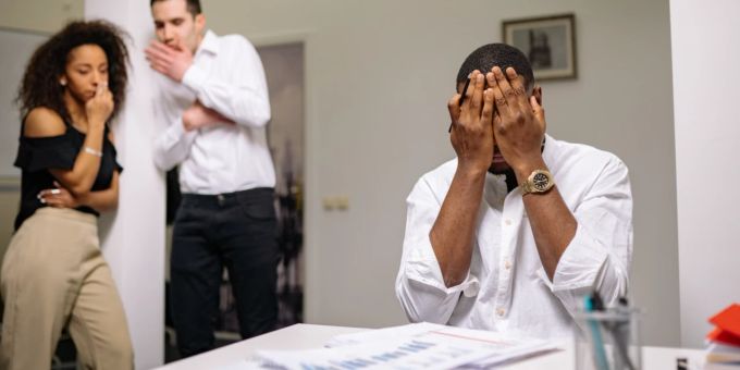 Vergiftet sich die Stimmung am Arbeitsplatz, spricht man auch von einem toxischen Arbeitsumfeld oder -klima. Mann Büro Bullying Kollegen Schreibtisch Psyche