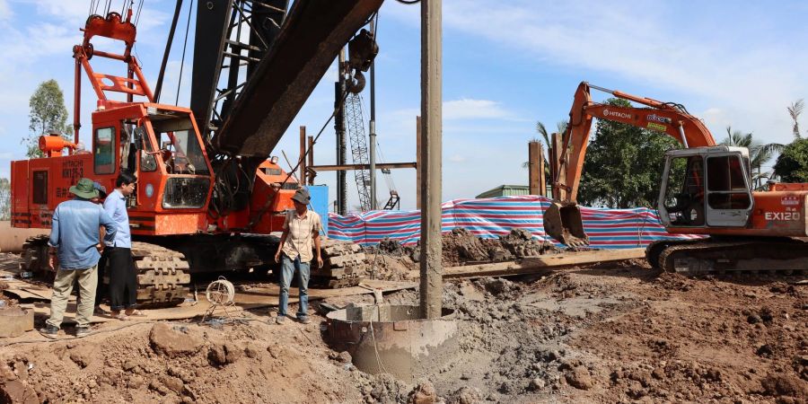 Rettungskräfte stehen an dem Rohr auf einer Baustelle in Vietnam.