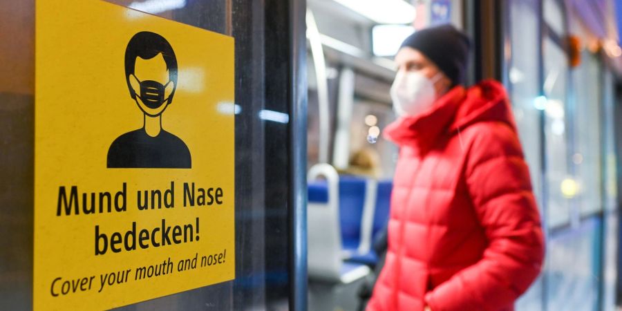 Eine Frau betritt mit FFP2-Maske eine Trambahn in München.