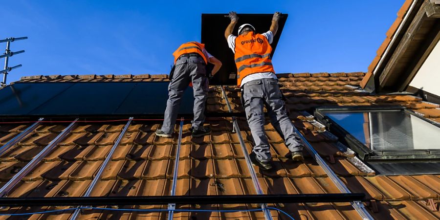 Arbeiter installieren eine Photovoltaik-Anlage im Kanton Freiburg. (Archivbild)
