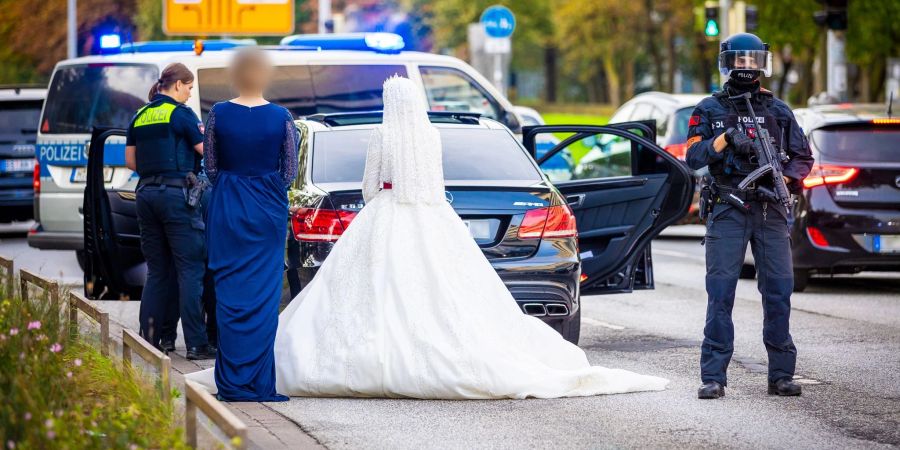 Polizisten kontrollieren Teilnehmer eines Hochzeitskorsos und ihre Fahrzeuge.