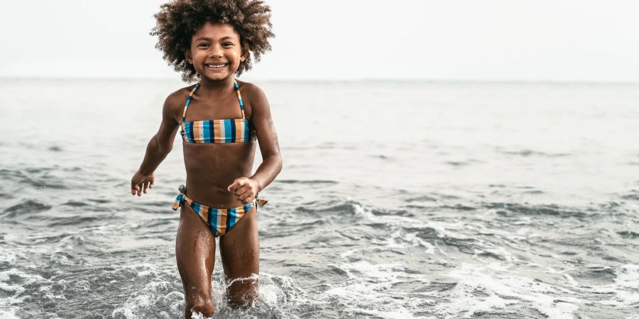 Schwarzes Mädchen in Bikini im Meer.