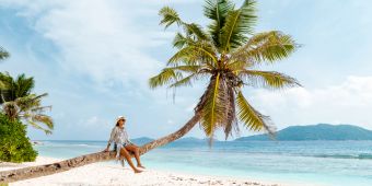 Frau auf Palme am Traumstrand, seychellen.