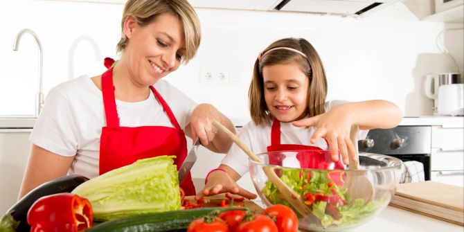 Frau und Mädchen bereiten Salat zu