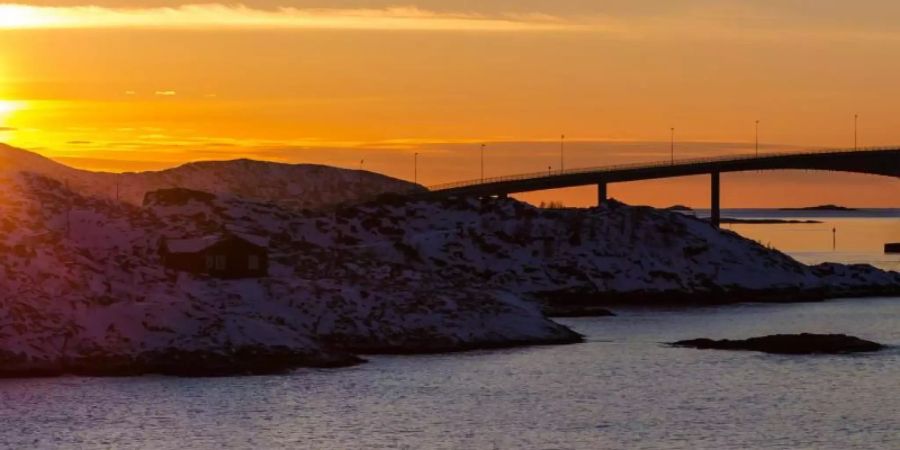 Die Sonne geht hinter der Sommaroy-Brücke unter, die die Inseln Kvaloya und Sommaroy verbindet. Foto: Hinrich Bäsemann