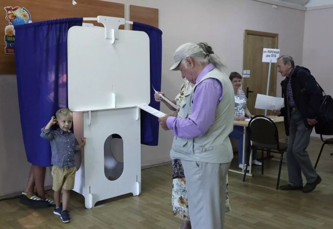 Wähler halten ihre Stimmzettel in den Händen in einem Wahllokal. Regionalwahlen in Russland