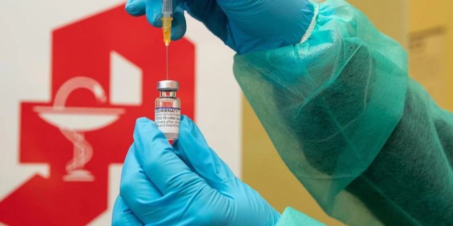 Eine Apothekerin zieht den Impfstoff Comirnaty vom Hersteller Biontech / Pfizer mit einer Spritze auf. Foto: Friso Gentsch/dpa