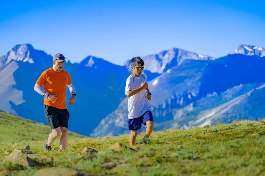 Mann Junge Wiese Feld Steine Trailrunning Berge Panorama