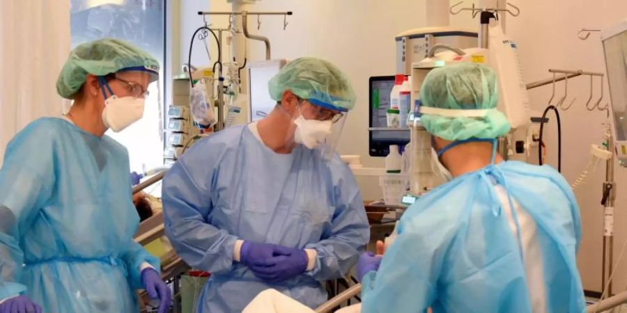 Auf der Covid-Station, einem Bereich der Operativen Intensivstation vom Universitätsklinikum Leipzig, stehen Mitarbeiter am Bett eines schwerkranken Patienten. Foto: Waltraud Grubitzsch/dpa-Zentralbild/dpa