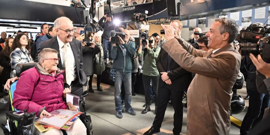 Bundespräsident Guy Parmelin und eine Besucherin werden von Ignazio Cassis fotografiert.