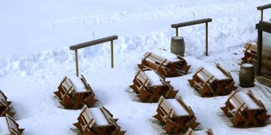 Schnee bedeckt Bänke und Tische an einer gesperrten Skipiste. Die österreichische Regierung hatte die Schliessung der Skigebiete angeordnet, um die Ausbreitung des Coronavirus zu verlangsamen. Foto: Matthias Schrader/AP/dpa