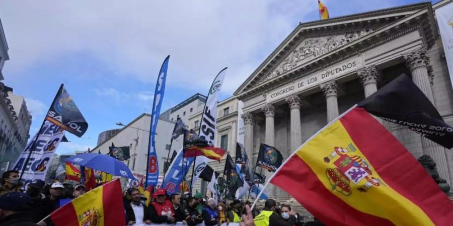 Polizisten laufen während des Protestmarsches am spanischen Parlament in Madrid vorbei. Foto: Paul White/AP/dpa