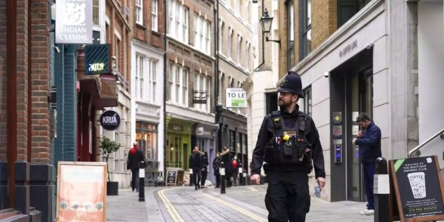 Ein Polizist läuft durch eine fast leere Strasse im Londoner Finanzdistrikt. Foto: Alberto Pezzali/AP/dpa